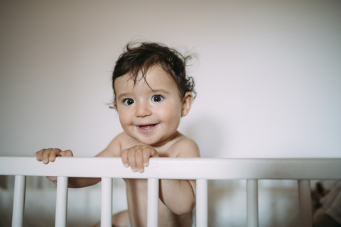 Porträt eines glücklichen kleinen Mädchens in einem Kinderbett, lizenzfreies Stockfoto