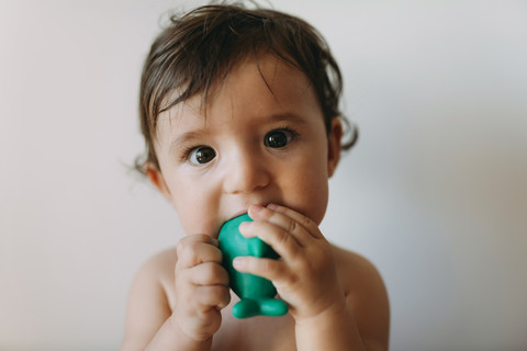 Porträt eines kleinen Mädchens, das in ein Plastikspielzeug beißt, lizenzfreies Stockfoto