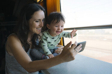 Glückliche Mutter und kleines Mädchen benutzen ihr Smartphone während einer Zugfahrt - GEMF01807