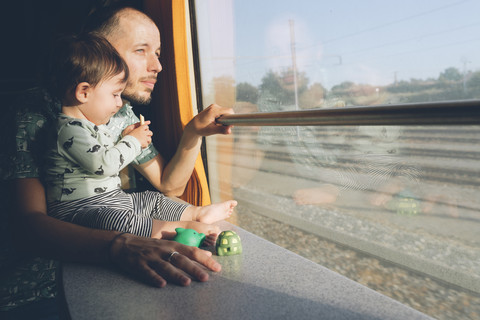 Vater und kleines Mädchen, die mit dem Zug reisen und aus dem Fenster schauen, lizenzfreies Stockfoto