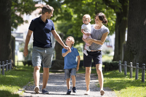 Happy family with two children walking in park stock photo