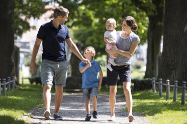 Glückliche Familie mit zwei Kindern beim Spaziergang im Park - MIDF00851