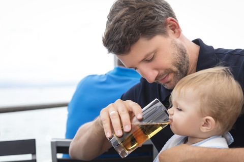 Father giving little daughter something to drink stock photo