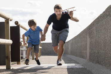 Father and son running with toy plane - MIDF00858