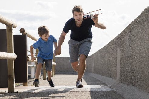 Vater und Sohn laufen mit Spielzeugflugzeug - MIDF00858