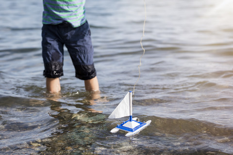 Boy playing with toy boat in water stock photo