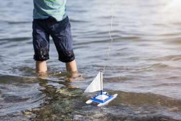 Boy playing with toy boat in water - MIDF00864