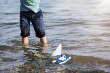 Junge spielt mit Spielzeugboot im Wasser - MIDF00864