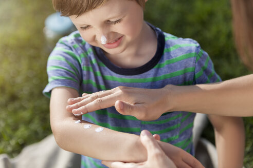 Mother applying suncream on son's arm - MIDF00868