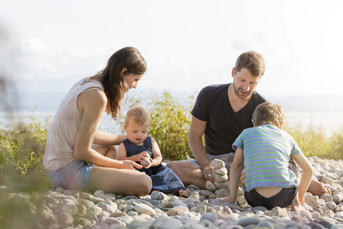 Deutschland, Friedrichshafen, Bodensee, Familie spielt mit Steinen am Seeufer - MIDF00870