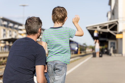 Sohn mit Vater winkt der Mutter auf dem Bahnsteig zu - MIDF00871