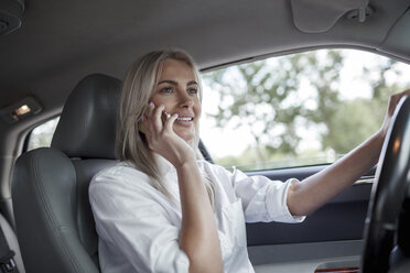 Lächelnde Geschäftsfrau am Handy beim Autofahren - VPIF00051