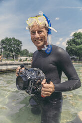 Porträt eines glücklichen Mannes mit Unterwasser-DSLR-Kameragehäuse in einem See - MFF03922