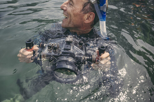 Glücklicher Mann mit Unterwasser-DSLR-Kameragehäuse in einem See - MFF03930