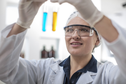 Scientist working in lab looking at test tubes stock photo