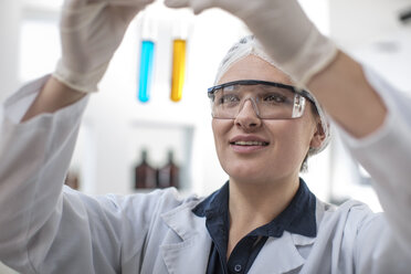 Scientist working in lab looking at test tubes - ZEF14585