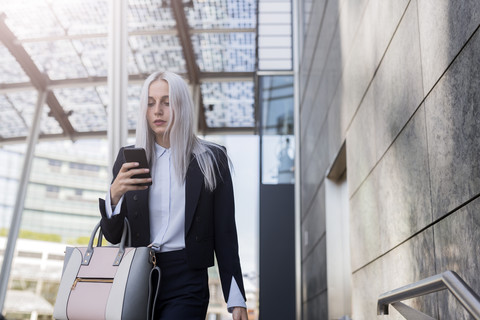 Junge Geschäftsfrau, die in der Stadt ihr Mobiltelefon überprüft, lizenzfreies Stockfoto