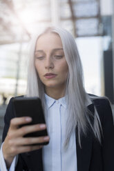 Junge Geschäftsfrau, die in der Stadt ihr Mobiltelefon überprüft - GIOF03193