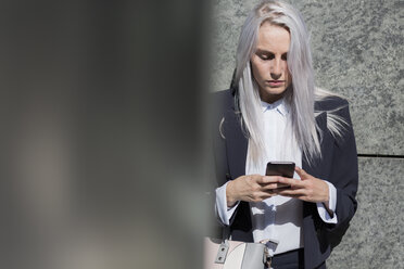 Young businesswoman checking cell phone in the city - GIOF03198