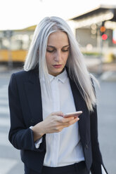 Young businesswoman checking cell phone in the city - GIOF03236