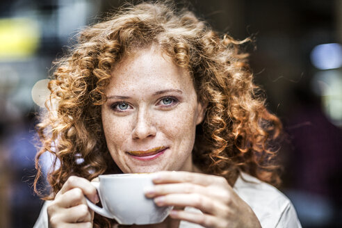 Porträt einer lächelnden jungen Frau mit Kaffeetasse - FMKF04480
