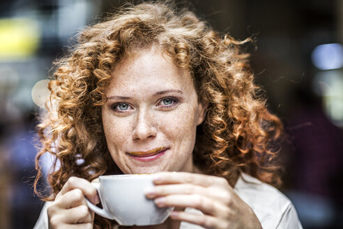 Portrait of smiling young woman with coffee cup - FMKF04480