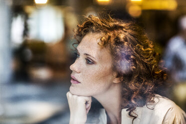 Portrait of pensive young woman behind windowpane - FMKF04483