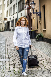 Deutschland, Köln, junge Frau mit Koffer in der Altstadt - FMKF04486