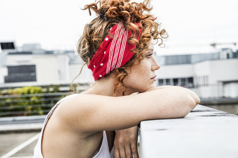 Serious redheaded woman leaning on wall stock photo