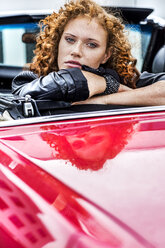 Porträt einer selbstbewussten rothaarigen Frau in einem Sportwagen - FMKF04519