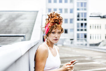 Portrait of redheaded woman holding cell phone - FMKF04522