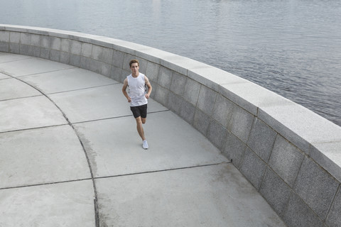 Young man running at the riverbank stock photo