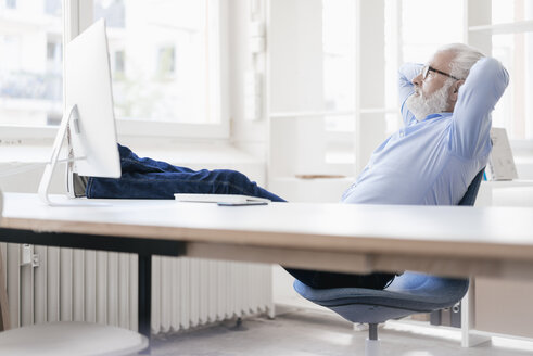 Älterer Mann mit Bart entspannt am Schreibtisch - JOSF01707