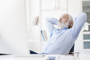 Mature man with beard relaxing at desk - JOSF01708