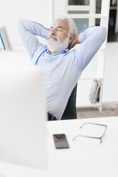 Älterer Mann mit Bart entspannt am Schreibtisch - JOSF01709