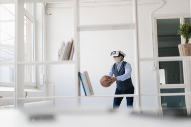 Älterer Mann mit VR-Brille spielt Basketball im Büro - JOSF01722