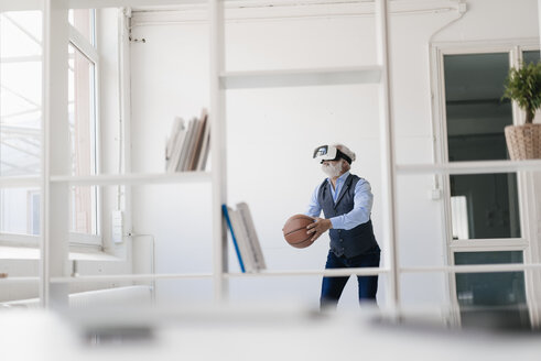 Älterer Mann mit VR-Brille spielt Basketball im Büro - JOSF01722