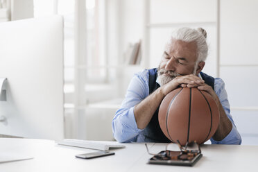 Entspannter reifer Mann am Schreibtisch mit Basketball - JOSF01725