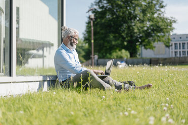 Älterer Mann mit Laptop auf einer Wiese - JOSF01732