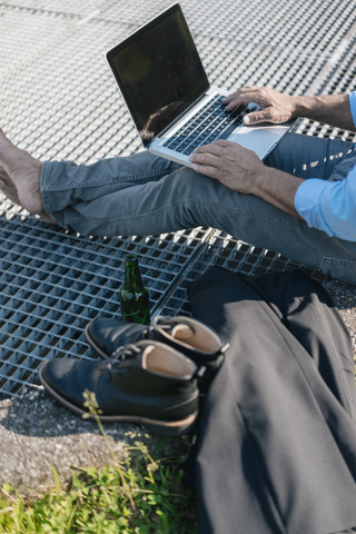 Mann mit Bier und Laptop im Freien, lizenzfreies Stockfoto