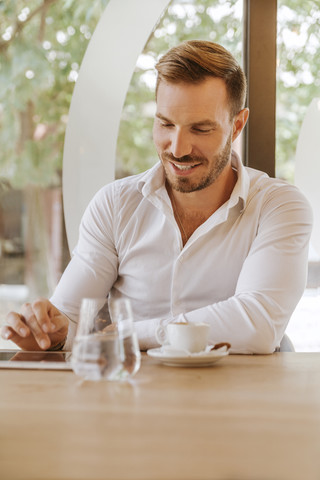 Smiling man with tablet in a cafe stock photo