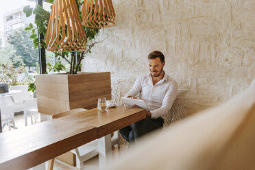 Smiling man with tablet in a cafe - ZEDF00849