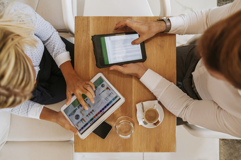 Geschäftsmann und Geschäftsfrau verwenden Tablets in einem Café, lizenzfreies Stockfoto