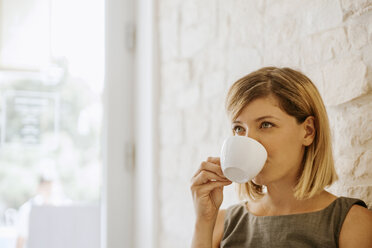 Young woman drinking cup of coffee - ZEDF00874