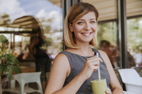 Porträt einer lächelnden jungen Frau mit Smoothie in einem Cafe - ZEDF00884