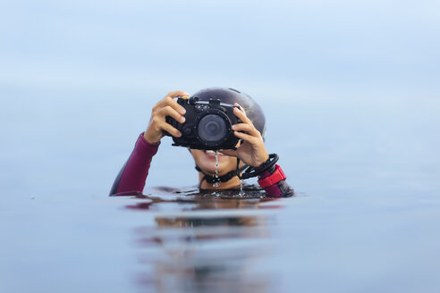 Lächelnde Frau hält Unterwasserkamera im Ozean - KNTF00898