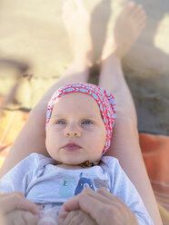 Porträt eines kleinen Mädchens, das auf den Beinen seiner Mutter am Strand liegt - LAF01884