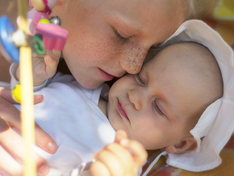 Kleines Mädchen und Schwester kuscheln auf einer Decke, lizenzfreies Stockfoto