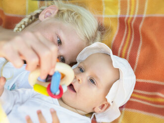 Girl playing with baby girl on blanket - LAF01889