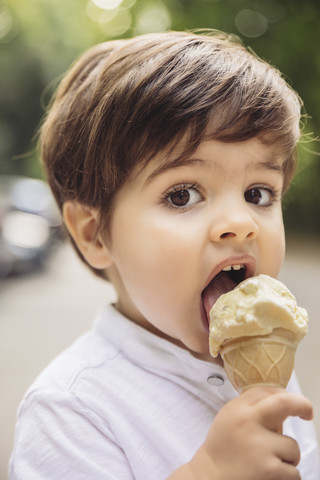 Portrait of toddler eating vanilla ice cream in park stock photo